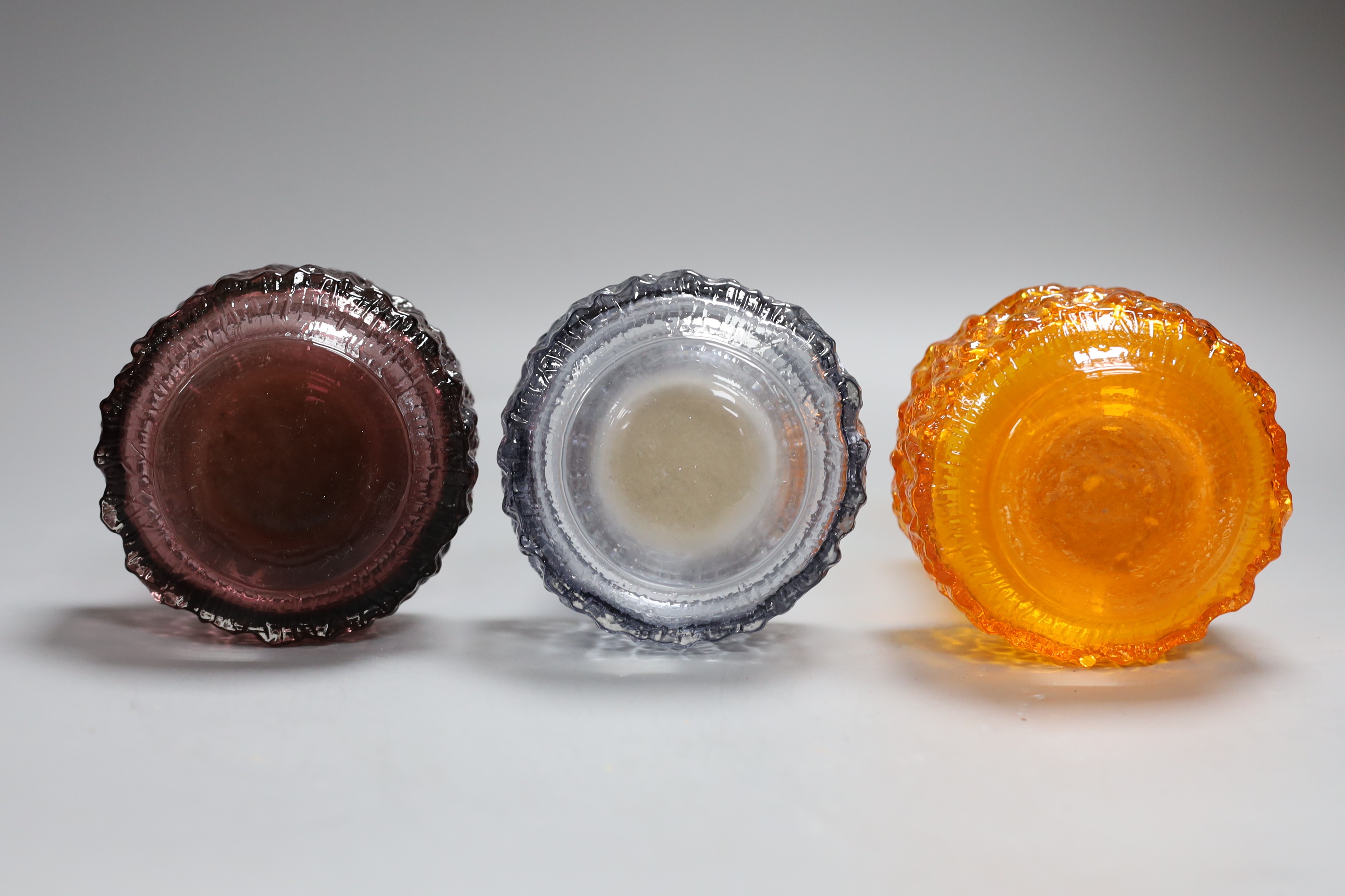 Three Whitefriars cylindrical bottle vases, in amethyst, tangerine and smoked glass, each 18cm high.